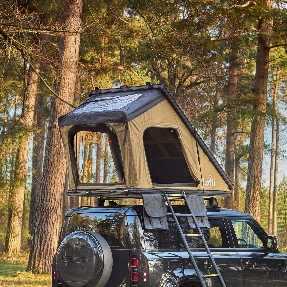 Lofti Millie slimline hard-shell rooftop tent on a Land Rover Defender in a forest